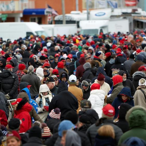 		hundreds of people crowded together, waiting for a public event to being. It is cold; most of them wear hats and coats
	