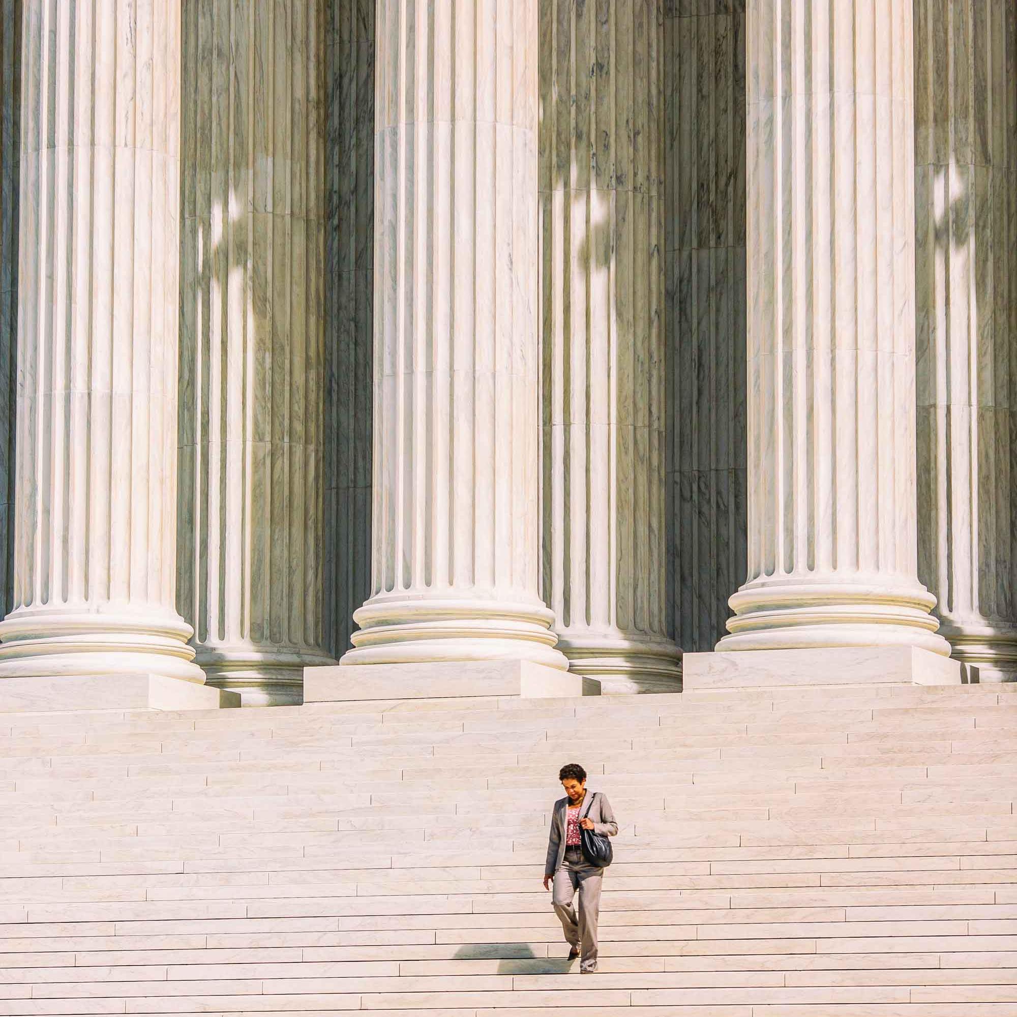 		Woman in business clothes walking down the steps of the Supreme Court with the tall columns behind her.
	