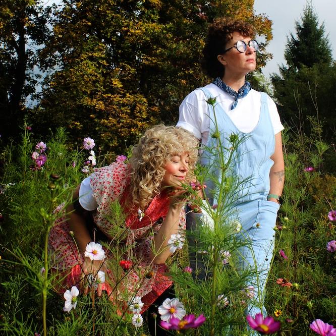 		Two people -- characters in a play -- stand in a field full of flowers
	