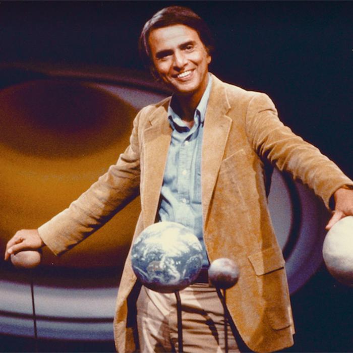 		Person in late-70s chic tan sport coat, touching models of planets
	