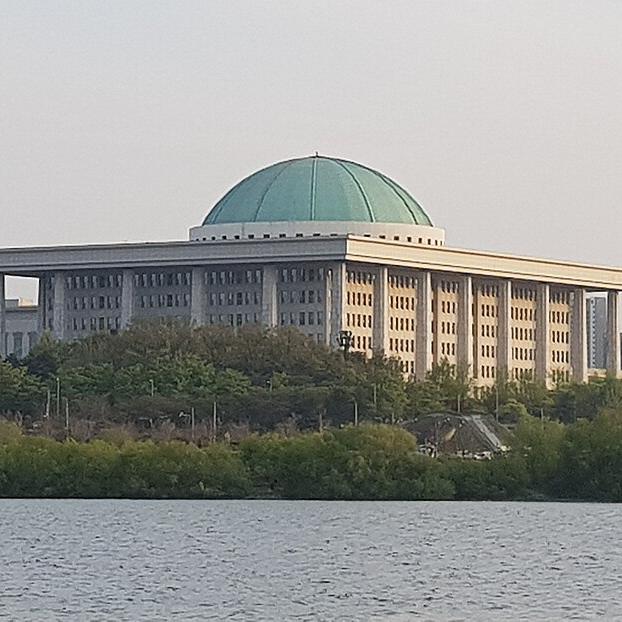 Public building with a green domed roof, beside a river