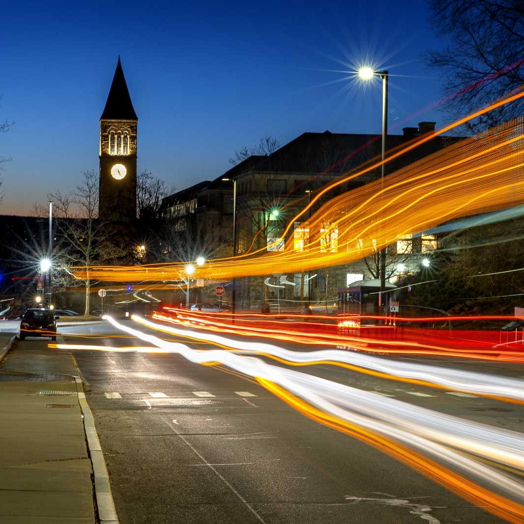 		Orange red and white horizontal streaks of light under a dark blue sky, showing automobile traffic in motion at night
	