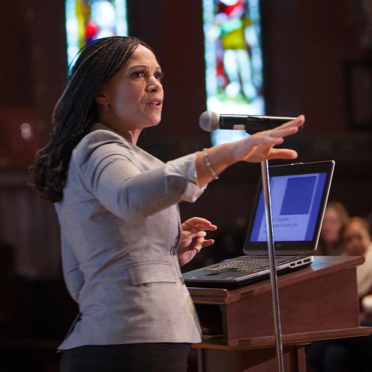 Person speaking at a podium with stained glass windows in the background