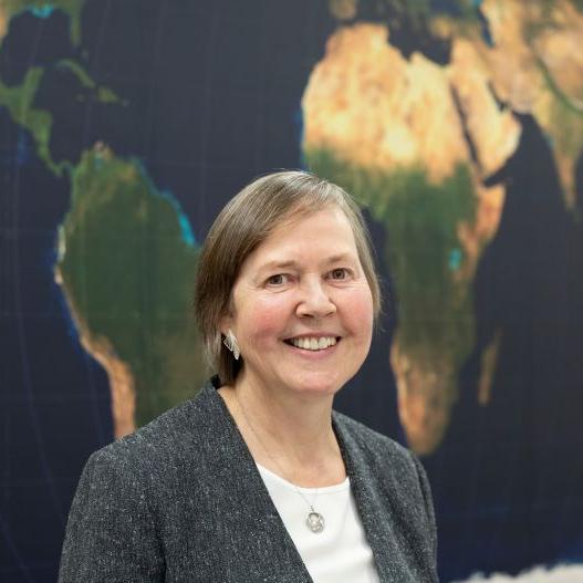 		Ellen Lust, smiling, standing in front of a map of Africa
	