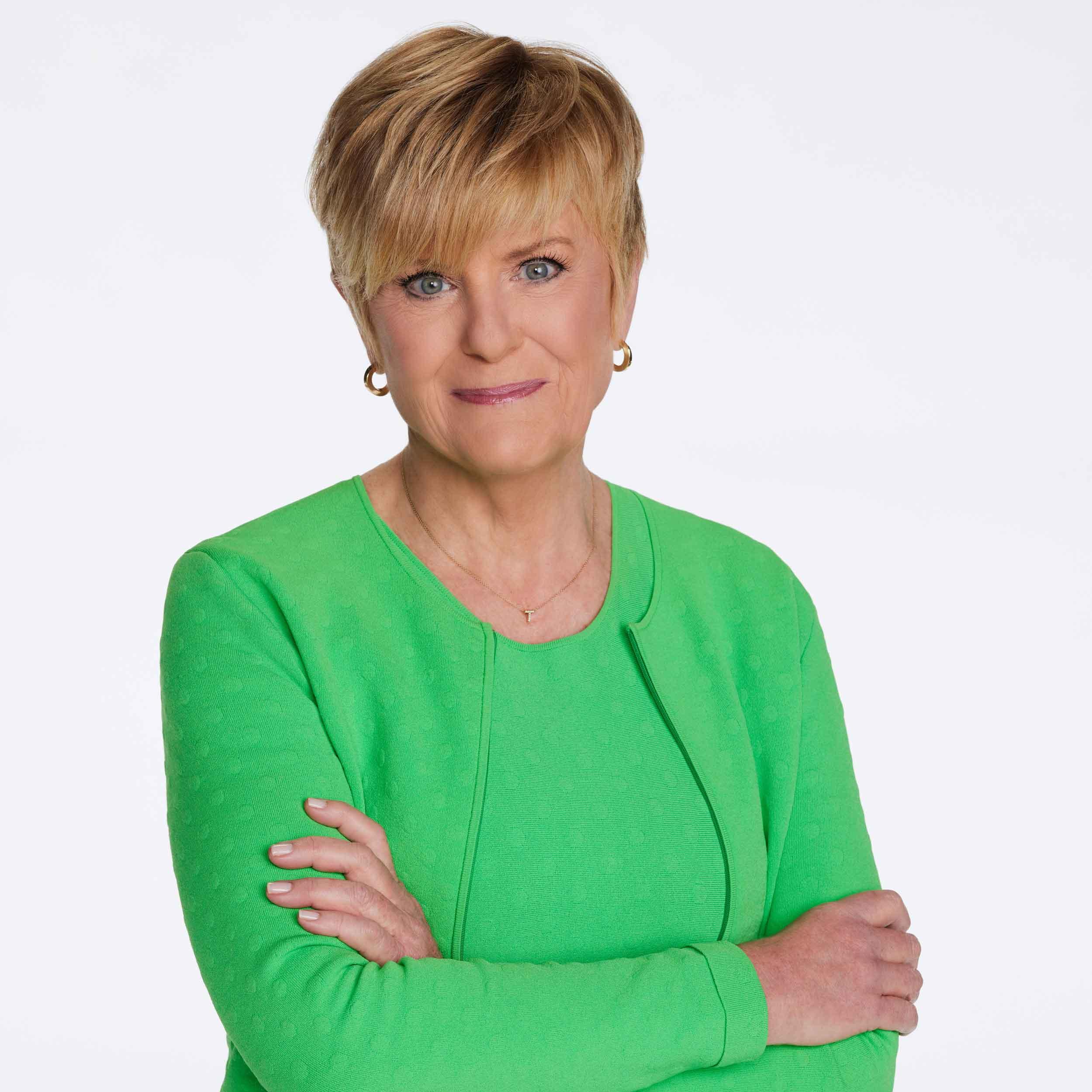 		Anne Thompson in green, long-sleeved dress with arms crossed, smiling.
	