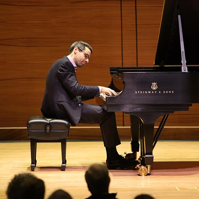 Person sitting at a grand piano, playing thoughtfully