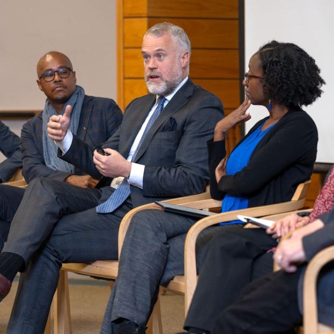 		Six people sit in a row, during a panel discussion event
	