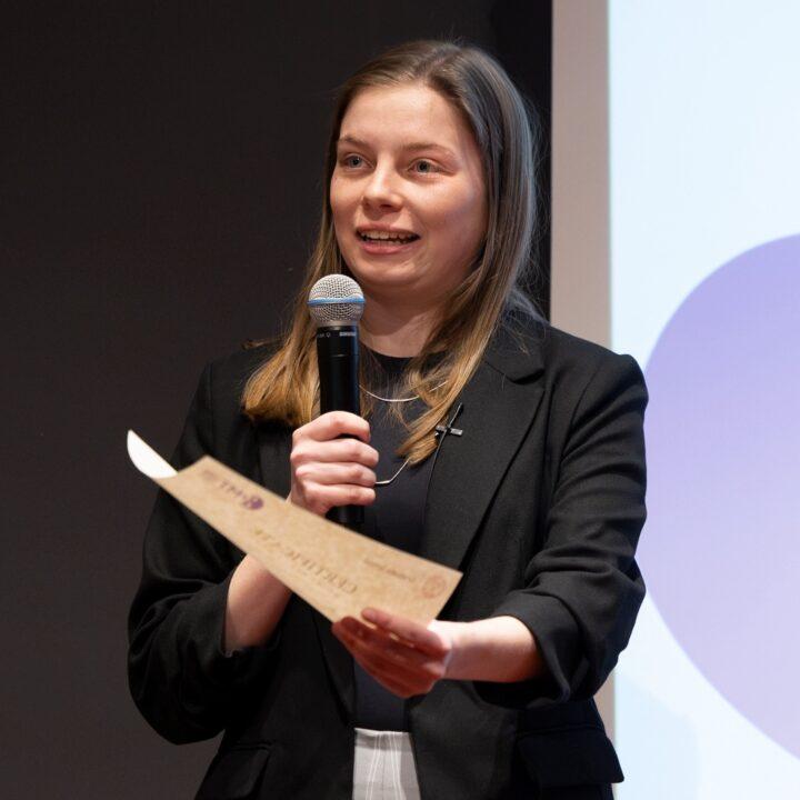 		Person holding a microphone and a certificate
	