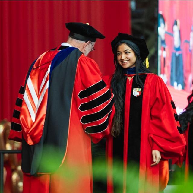 		Person in academic robes shakes the hand of another person in academic robes
	
