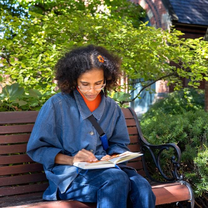 		Person sitting on a bench under a tree, reading a book
	