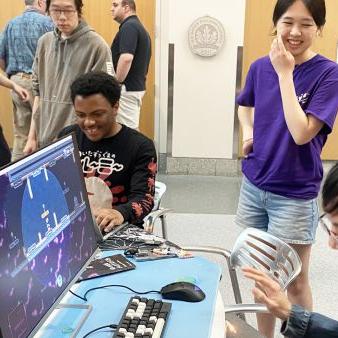 		Several people in a room, laughing, with a video game on a large screen
	