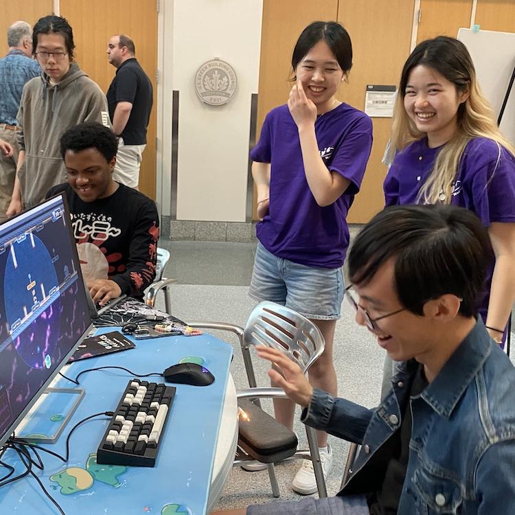 		Several people gathered around a table with computer games
	