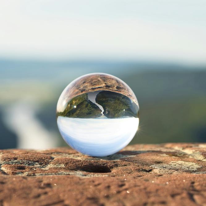 		crystal ball reflects a view of a river, upside down
	