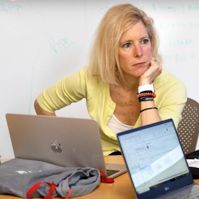 		person at a desk with computers, looking thoughtful
	