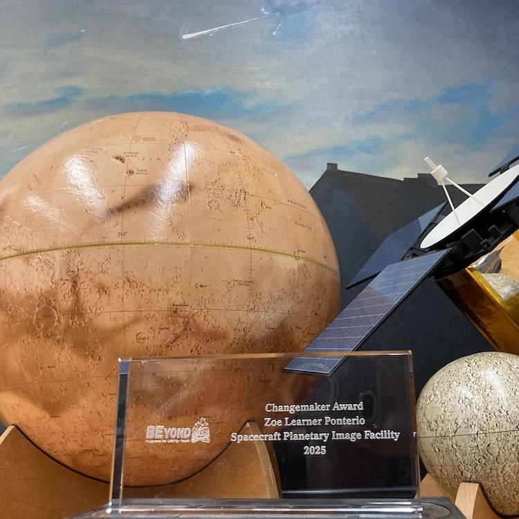 Rectangular glass award set among model planets on a table