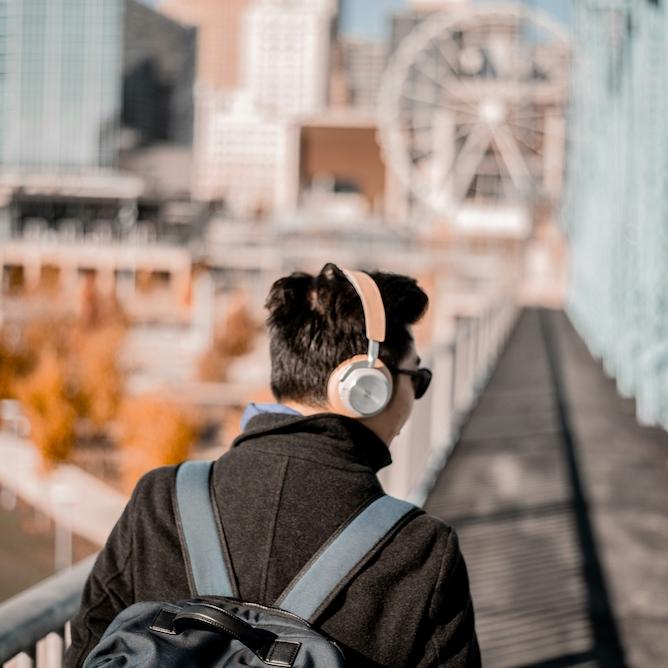 		Person wearing pink headphones, walking outdoors in a city
	