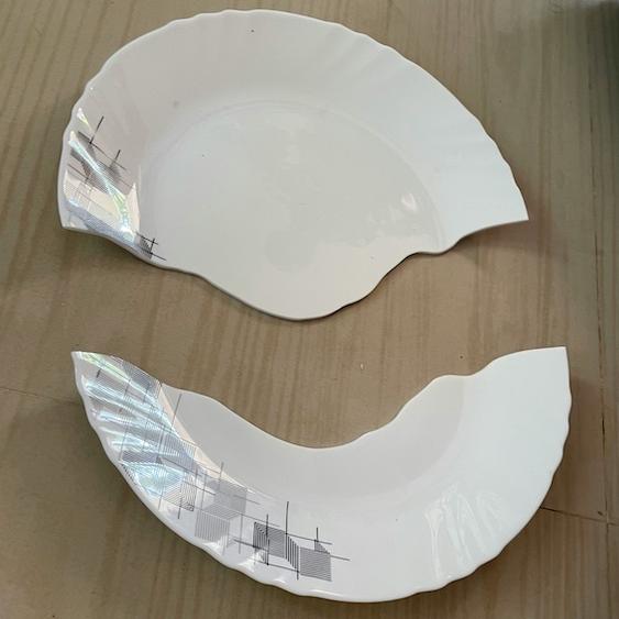 White plate, broken in half on a wood floor