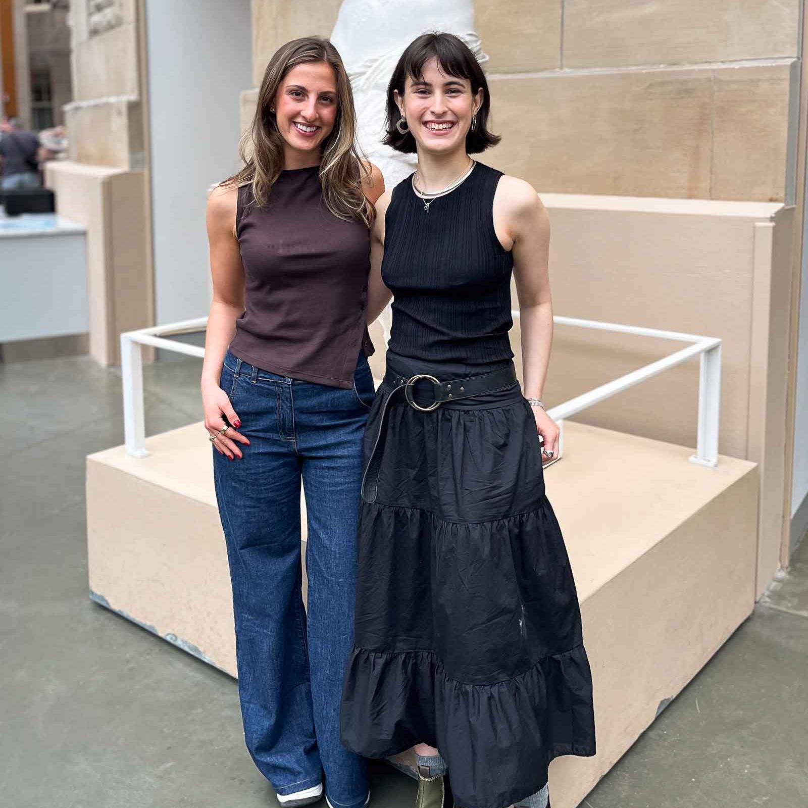 		two people standing in front of a statue
	