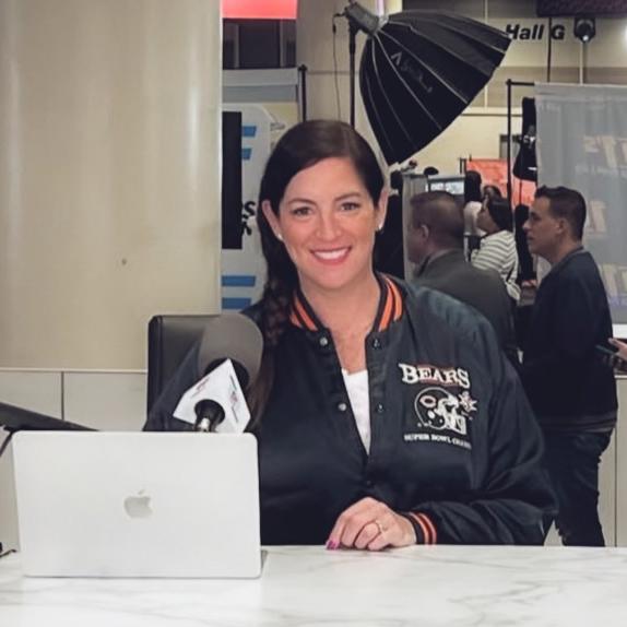 Person wearing a Bears jacket sitting at a computer in a press room