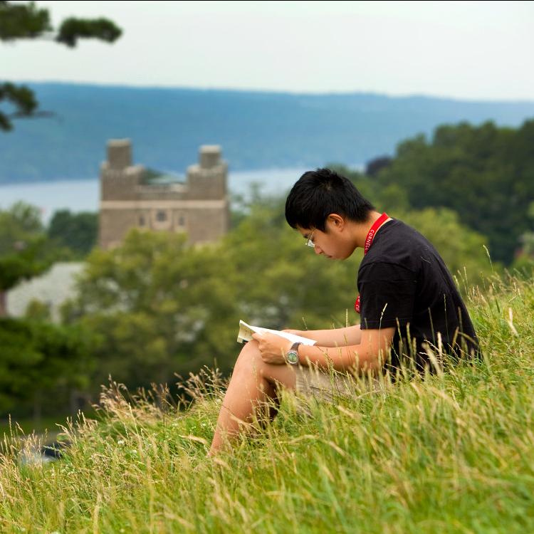 		Person sitting in tall grass on a hilside, reading a book
	