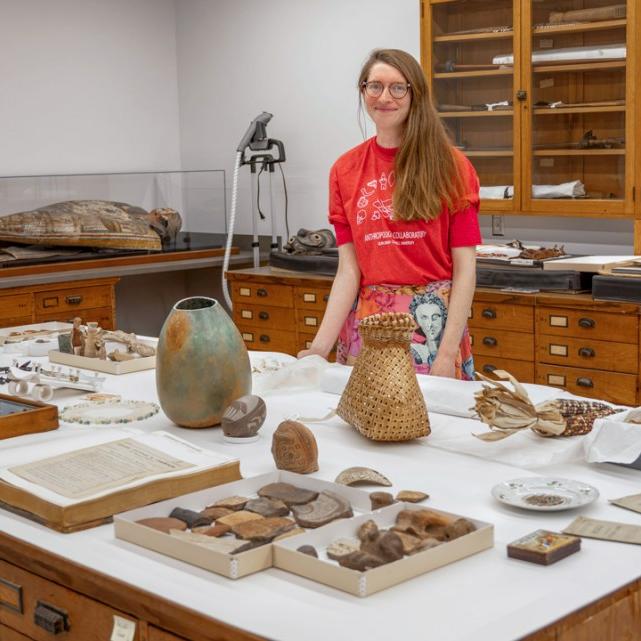 		Person standing behind a table covered with artifacts
	