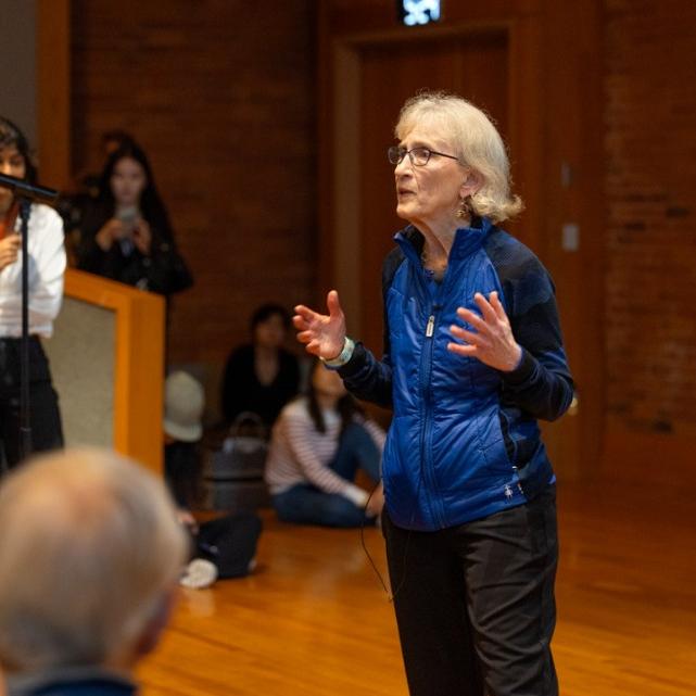 Person speaking in front of an audience in a packed auditorium