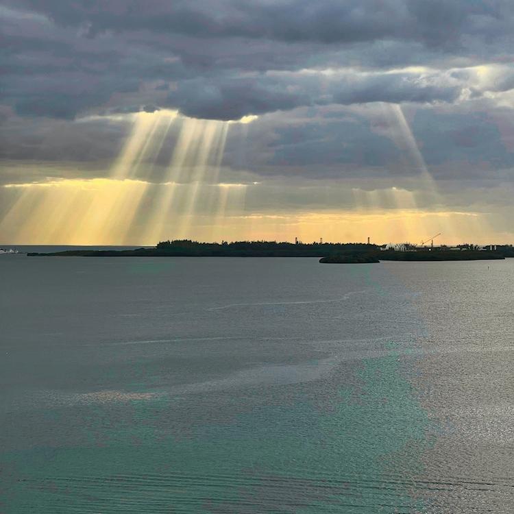 		Sun beams shoot through heavy clouds over a bay
	