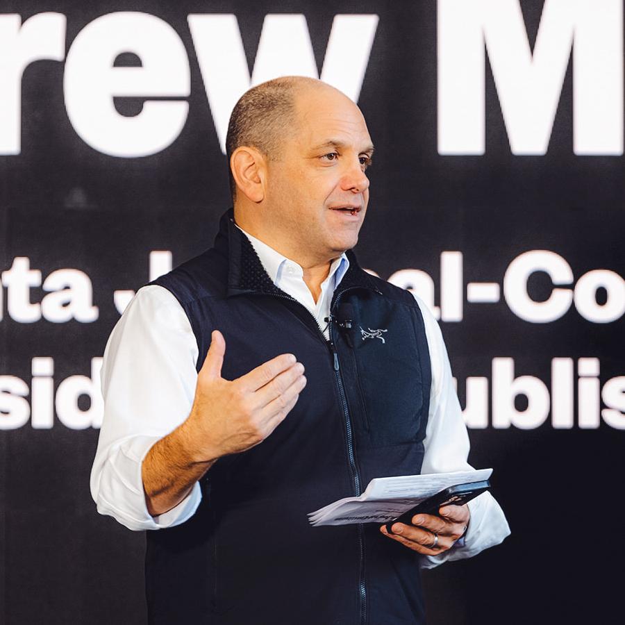 Person wearing a black vest and white shirt, speaking publically