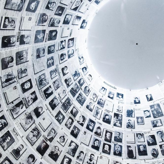 hundreds of black and white portrait photos on a wall leading up to a light grey dome