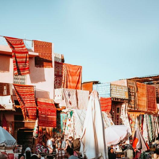 		Colored rugs make a collage under a blue sky
	