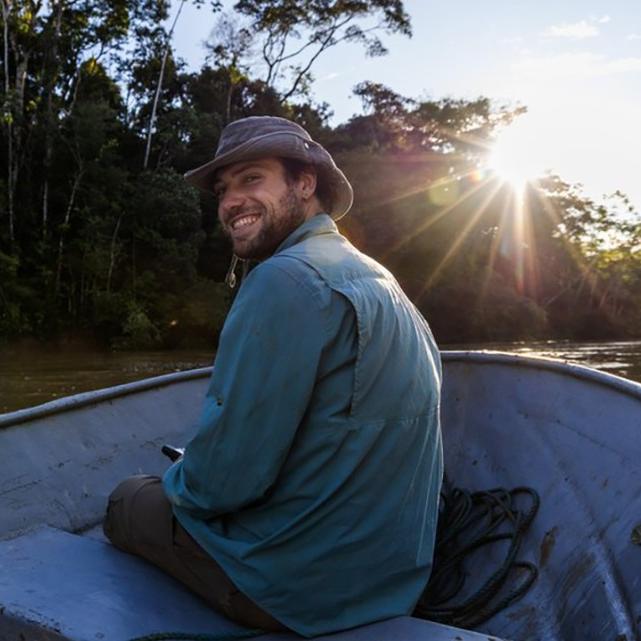 Person in a small boat on a river, turning around and smiling
