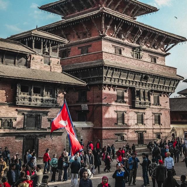 People standing in front of a big brick building with three levels of pagoda-style roofs