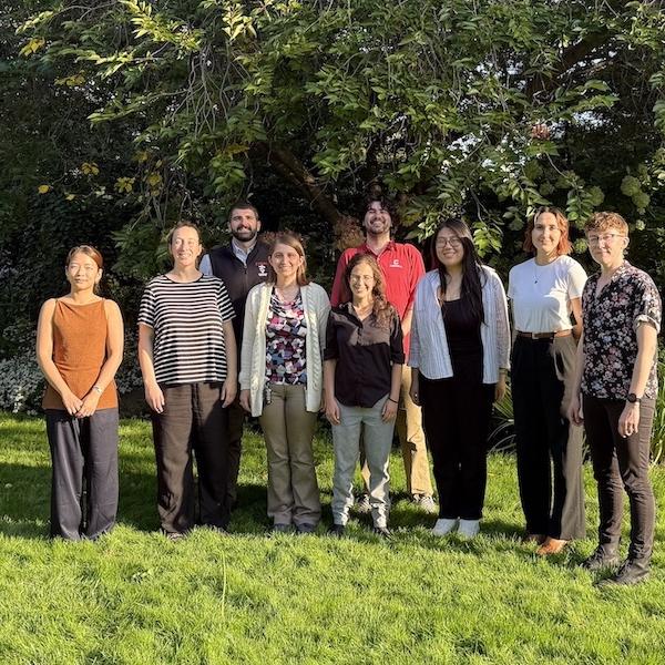 		Nine people standing in a grassy area
	