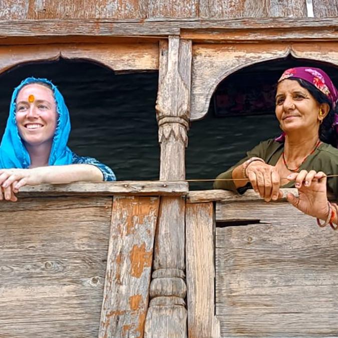 Two people leading out of windows in a wooden building