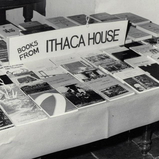 Black and white photo of a tale covered with books for sale from "Ithaca House" press