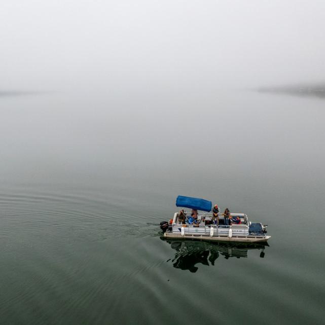 		Pontoon boat on still, gray water
	