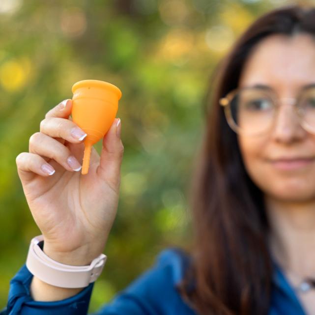		Person holding up an orange menstrual cup
	