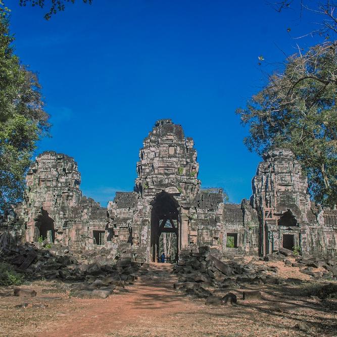 ancient stone temple surrounded by trees, under a bright blue sky