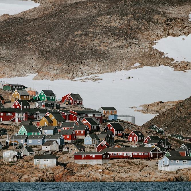 Hill with dozens of colorful houses on it, backed by a bleak landscape with snow