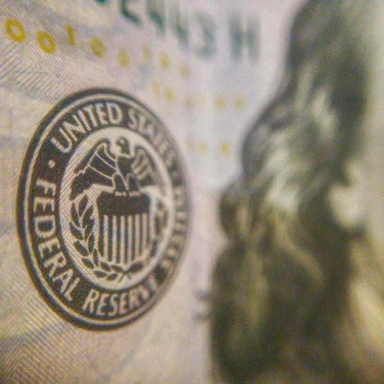 		Circle on textured paper that says 'Federal Reserve'; an extreme close up of a one-dollar bill, US
	
