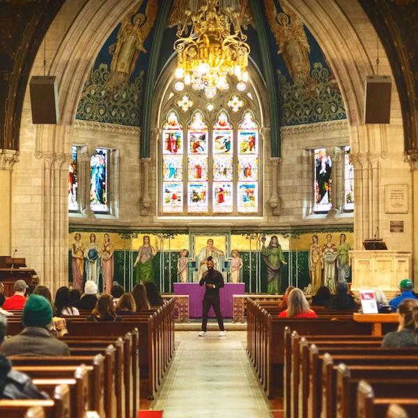 		Colorful interior of a chapel with a vaulted ceiling; people sit in the pews facing a person speaking at the front
	