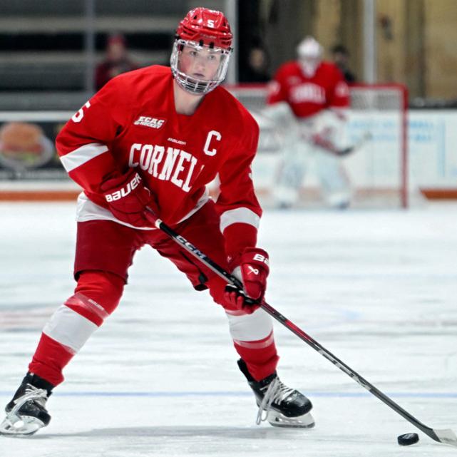 		Person in red hockey gear, puck near the stick
	