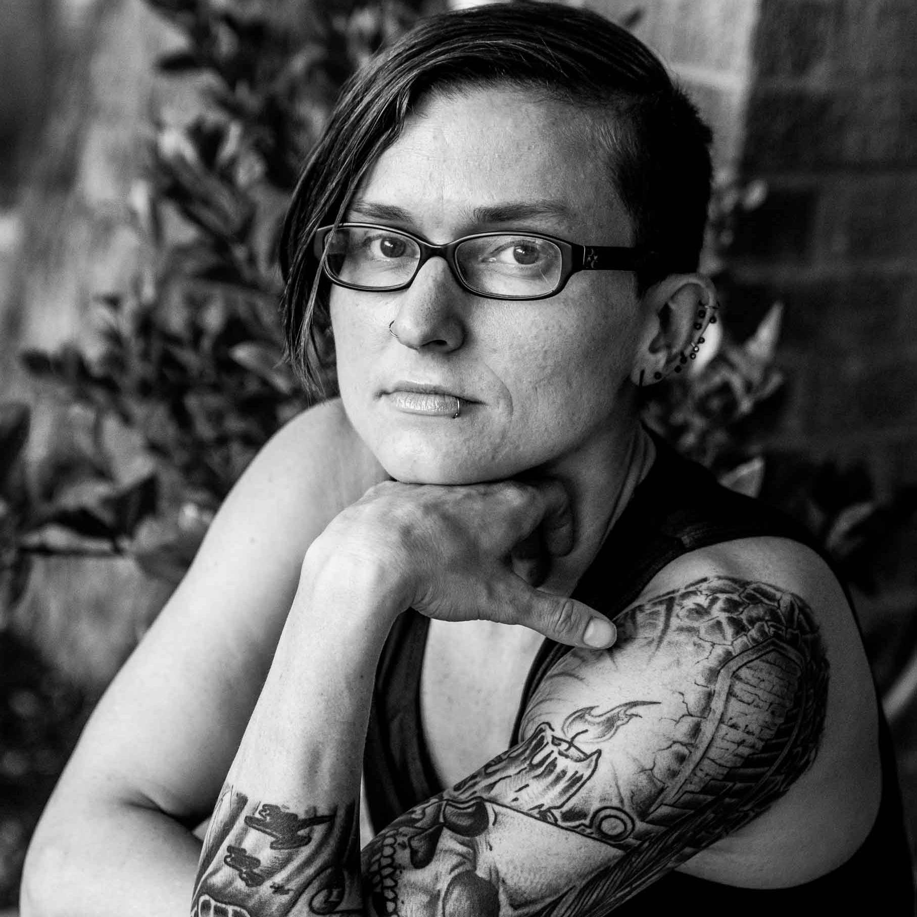 Keri Blakinger with short hair, tattoos on her arm wearing multiple bracelets