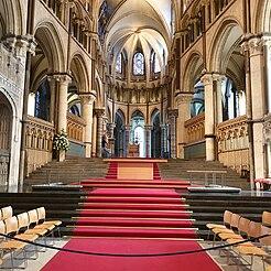 		Columns and arches form the walls, with a red carpet leading up to the alter in this image of the interior of the cathedral 
	
