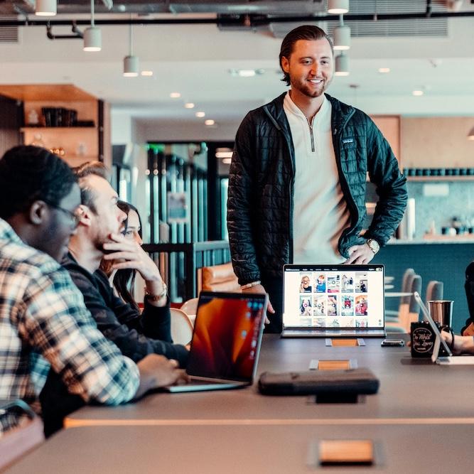 Person standing befor others, a computer open, looking confident