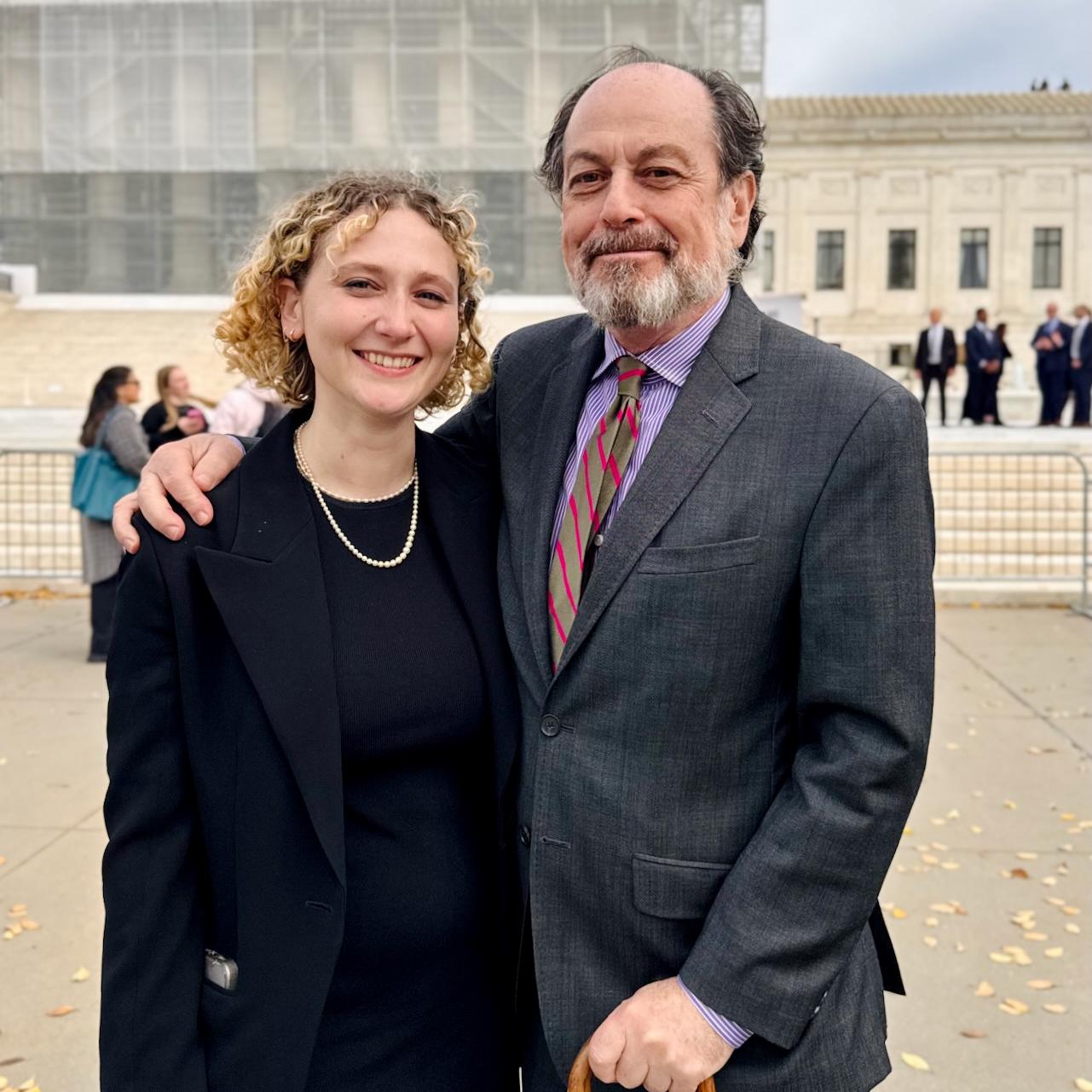 Two people dressed very well stand together in front of a large building