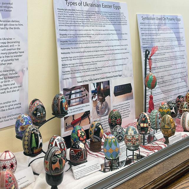 A display case filled with colorful Easter eggs and interpretive posters