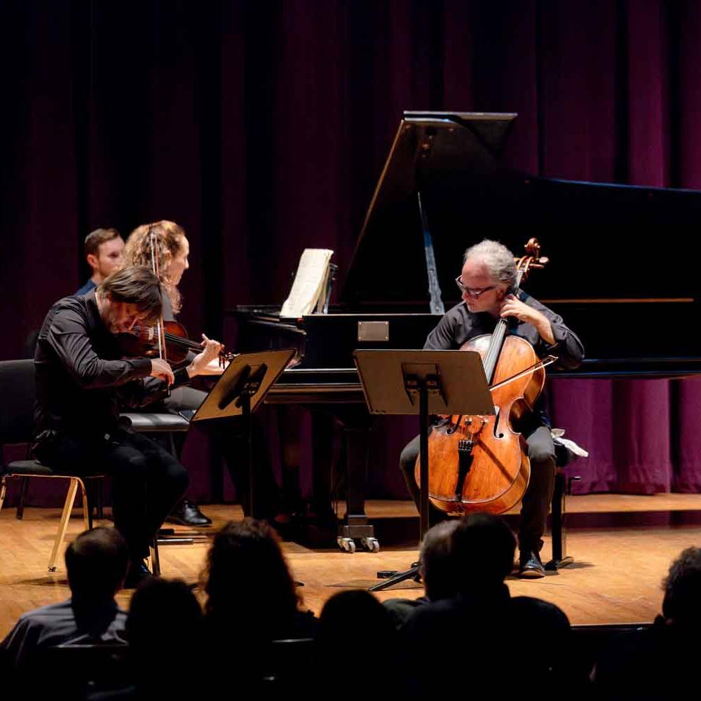 three people playing instruments on stage