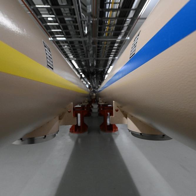 Close up of two very large tubes, the one on the left with a yellow stripe, the one on the right with a blue stripe