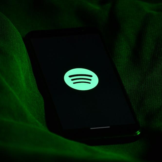 Green circle Spotify logo with black sound waves against a dark backgroun